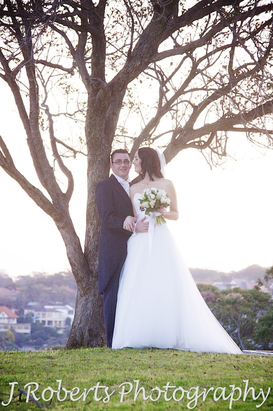 Bride looking at the groom under tree with setting sun - wedding photography sydney